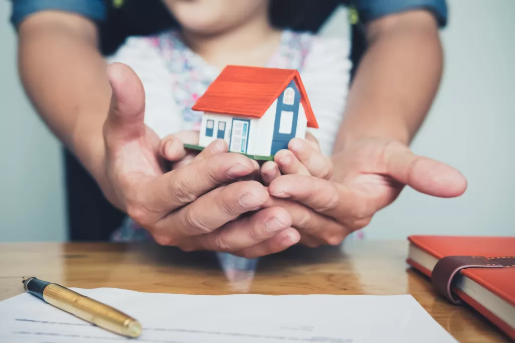 child and adult holding home model over a contract